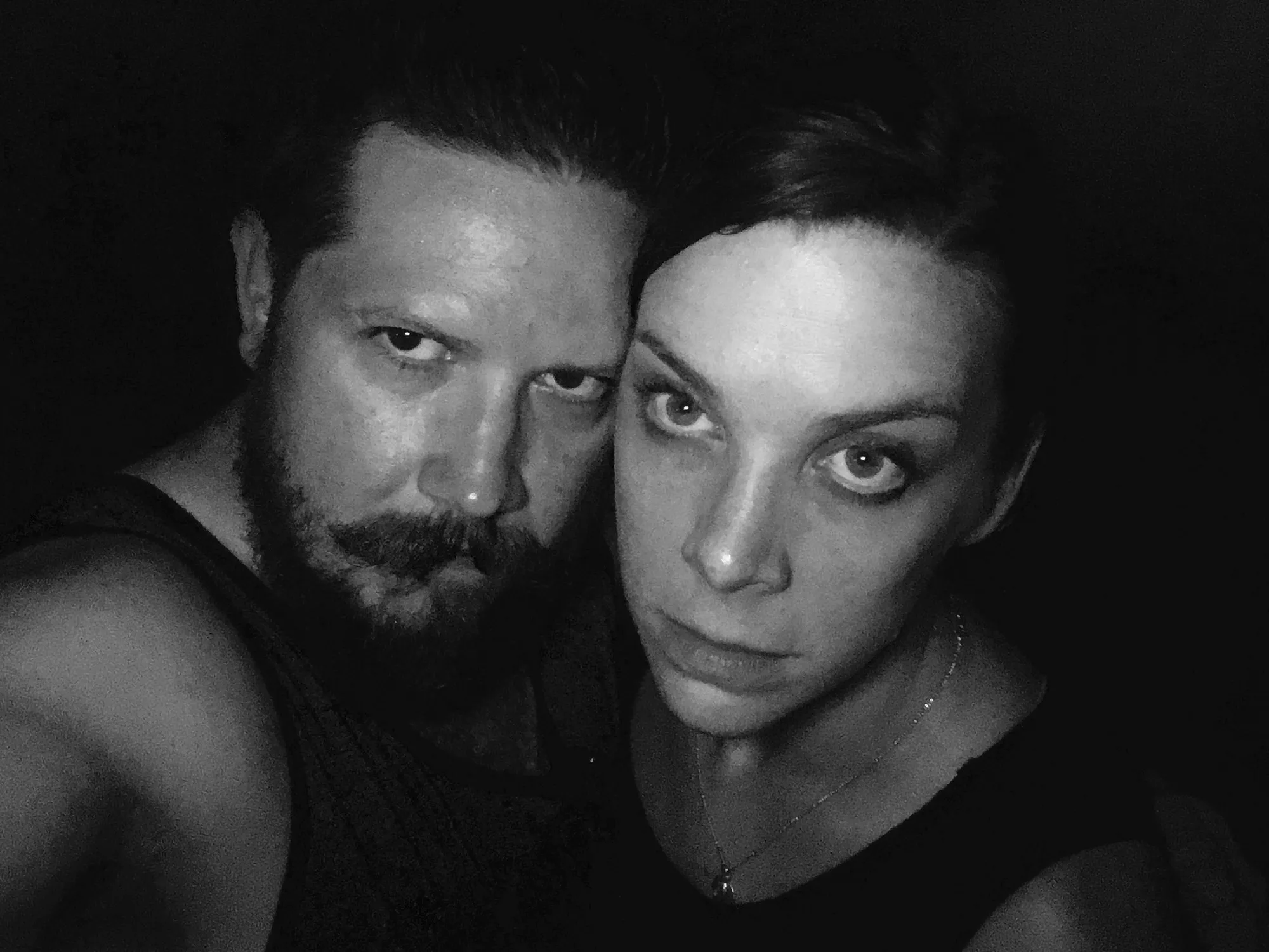Ammon and Jenny, close together in the dark, staring straight into the camera